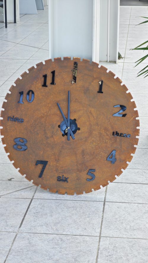 Wanduhr aus einem Sägeblatt mit Fahrzeugteilen als Zeiger