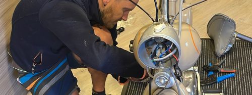 Schrauber montiert einen Scheinwerfer an einem klassischen Fahrzeug